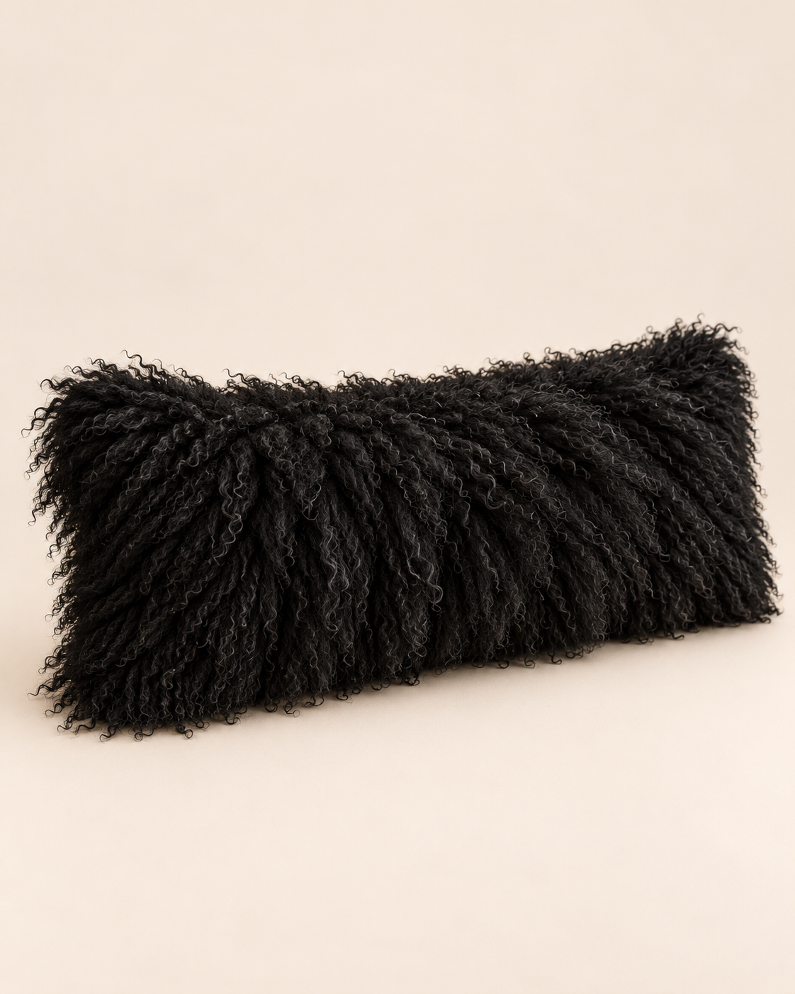 Black rectangular Mongolian sheepskin cushion viewed at an angle